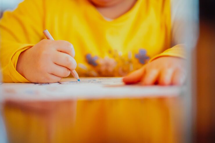 Närbild på barns händer ritar vid ett bord
