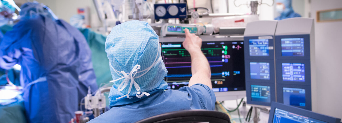 En person i operationskläder pekar på en skärm i en operationssal.