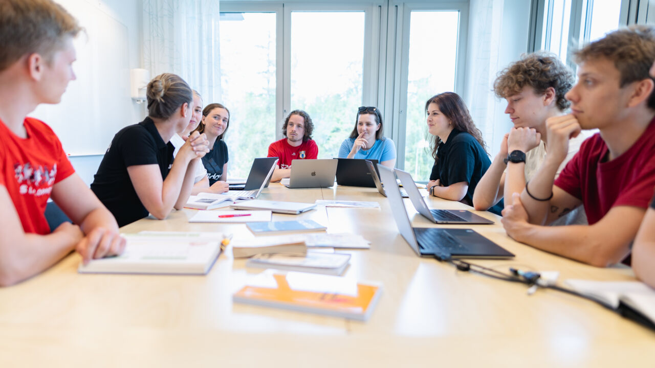 Studenter i basgrupp runt ett bord i ett grupprum