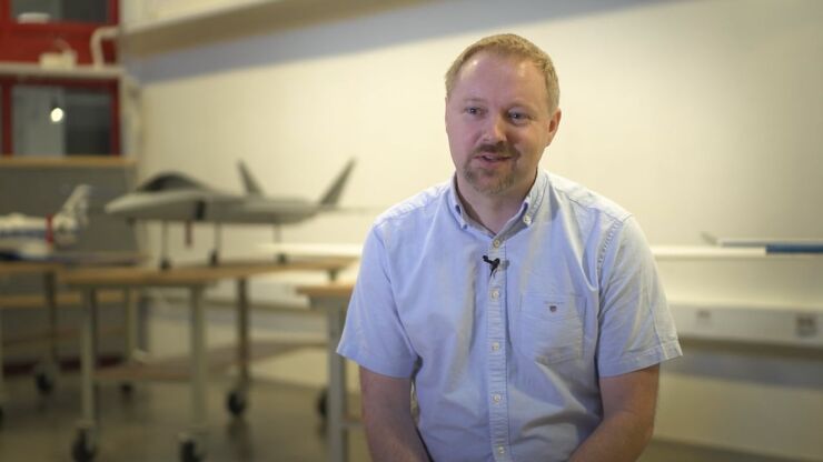 Man in light shirt with aircraft model in the background