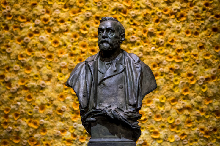 bust of Alfred Nobel in front of yellow flower wall