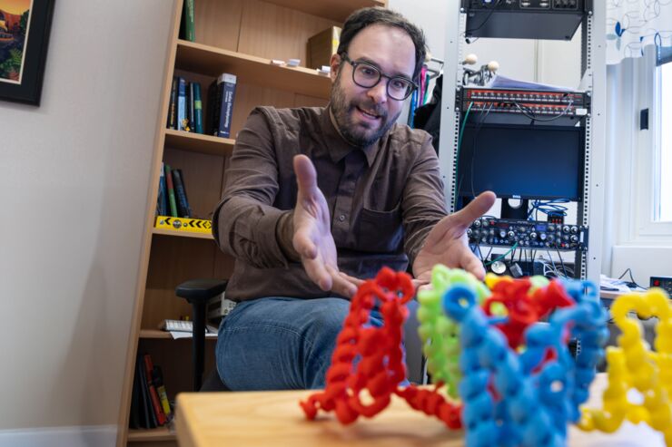 Researcher Antonios Pantazis sits in his office and shows his 3D model of ion channels in different colors.