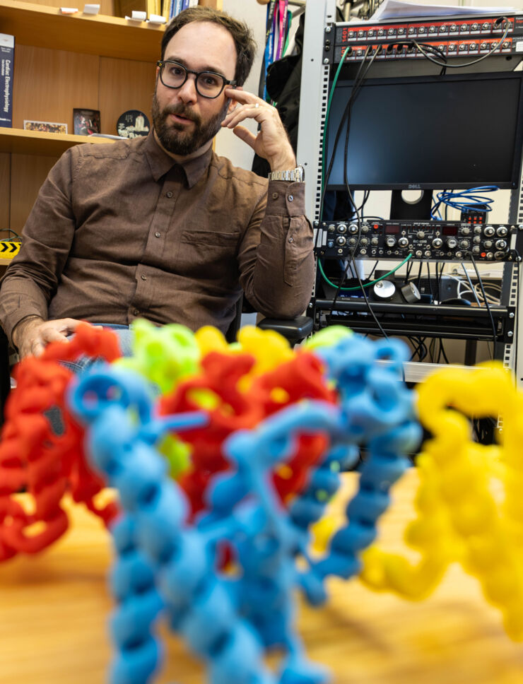 Antonios Pantazis in his office with his 3D model of ion channels in front of him.