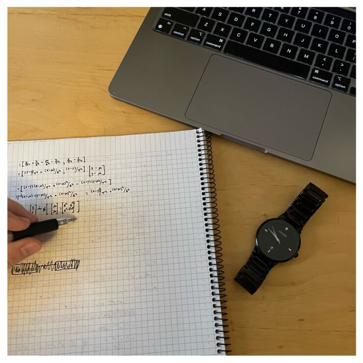 Picture of a table showing a computer, watch, pen and paper.