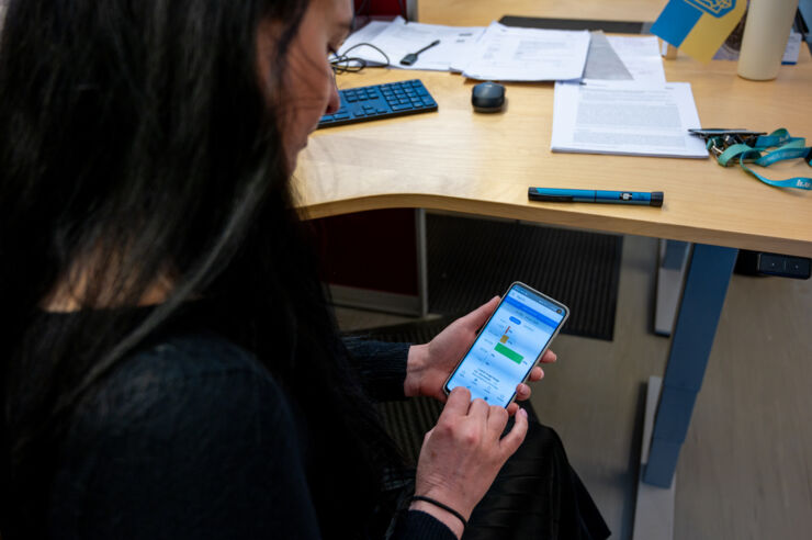 En kvinna använder mobilen för att få fram information om sockernivå i blodet.