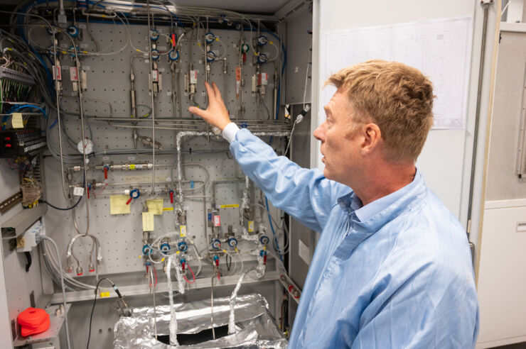 Person in o blue coat shows the inside of a machine.