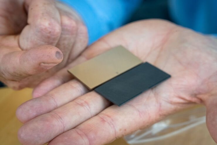 En svart och en guldfärgad rektangulär platta i en hand.