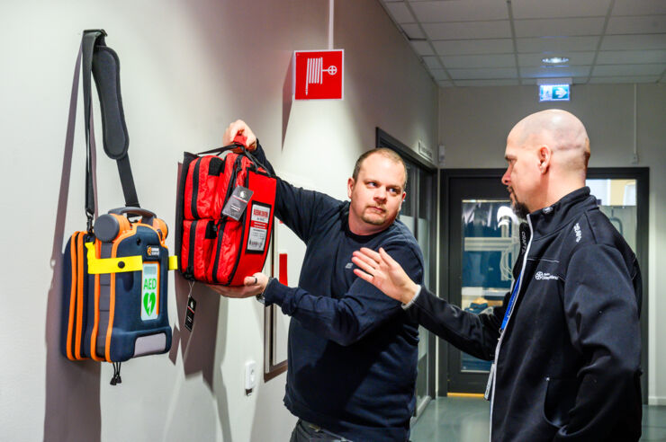Two men fetching bleed control equipment located next to an AED.