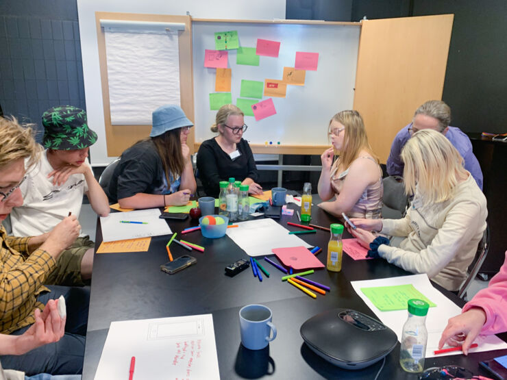 Young adults around a big table working with colourful papers.