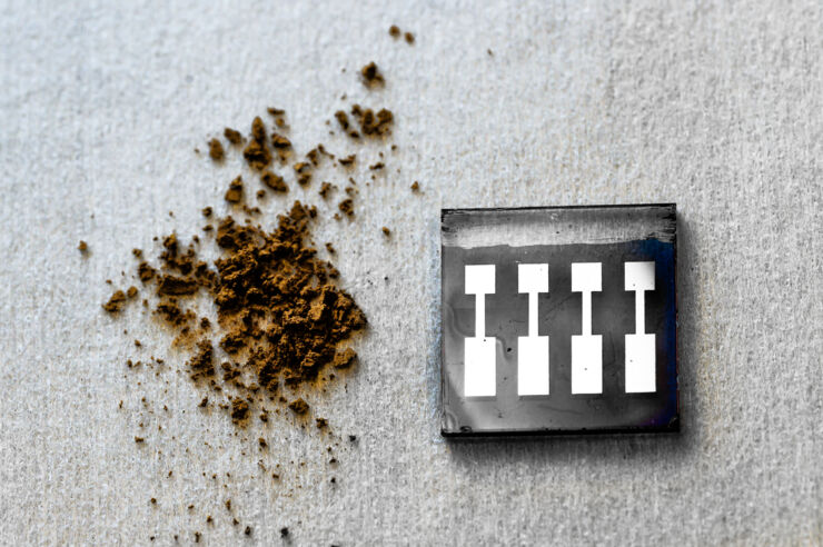 A small pile of brown powder (kraft lignin) next to an organic solar cell.