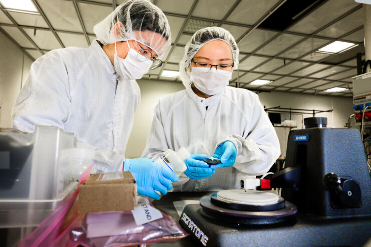 Two persons in labcoats and facemasks.