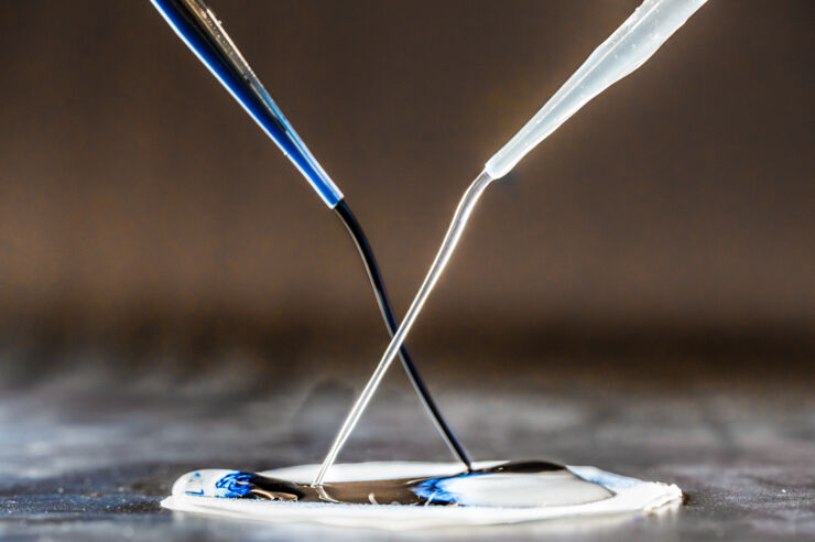 Two pipettes poring liquids on to a disk.