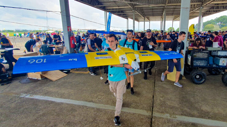 Student som bär ett modellflygplan till start.