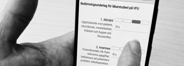 En hand håller fram en mobiltelefon med ett formulär.