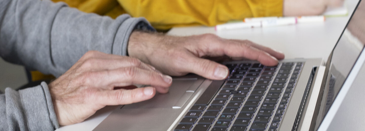 Person writing on a laptop keyboard.