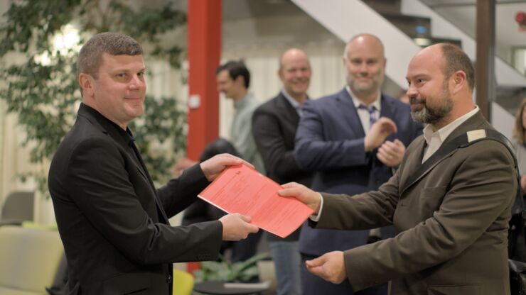 Frans Oliehoek hands over a document to Johan Källström