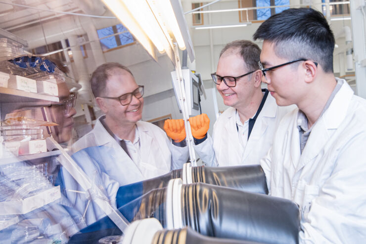 Three happy male researchers in lab coats.