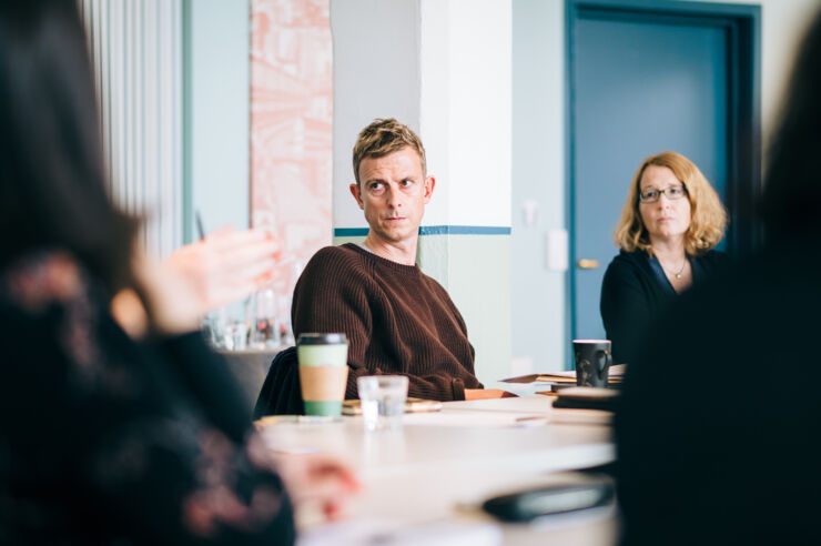 A person in a conference room is intensely listening to someone else talking