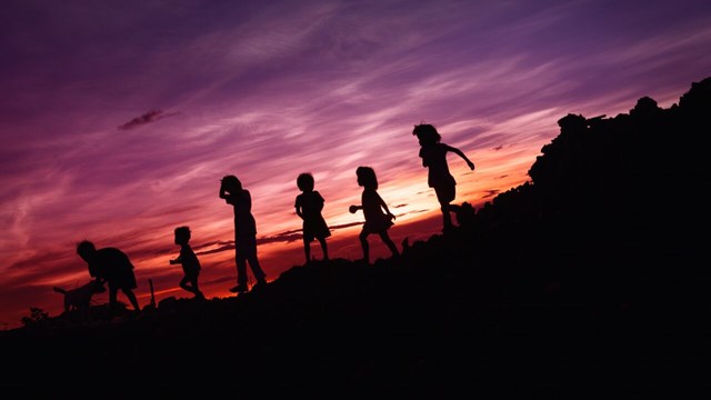 Siluett av flera barn i solnedgången