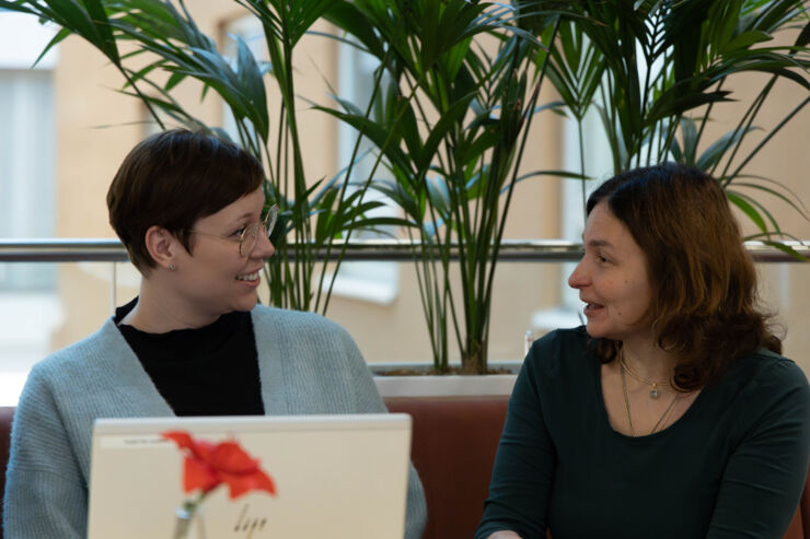 Two women talk to each other sitting on a couch.