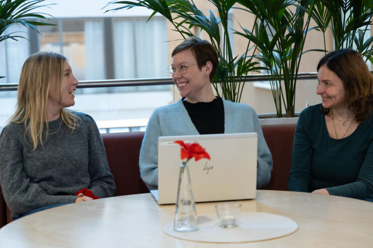 Three women laughing on a sofa.