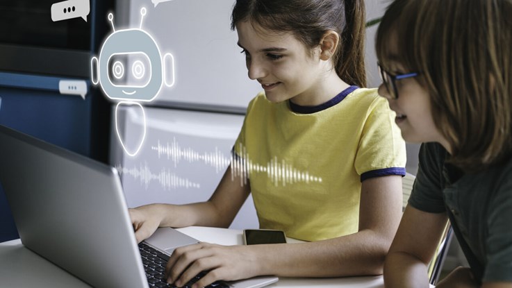 Två flickor vid en dator och de använder en AI chatbot.