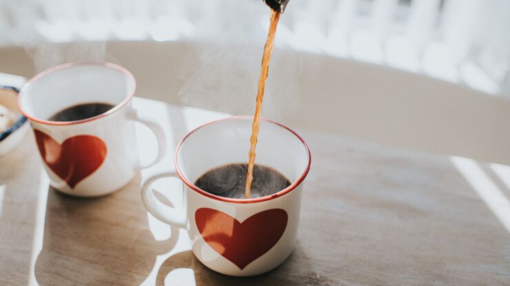 Kaffe hälls ner i en kopp med ett hjärta på.