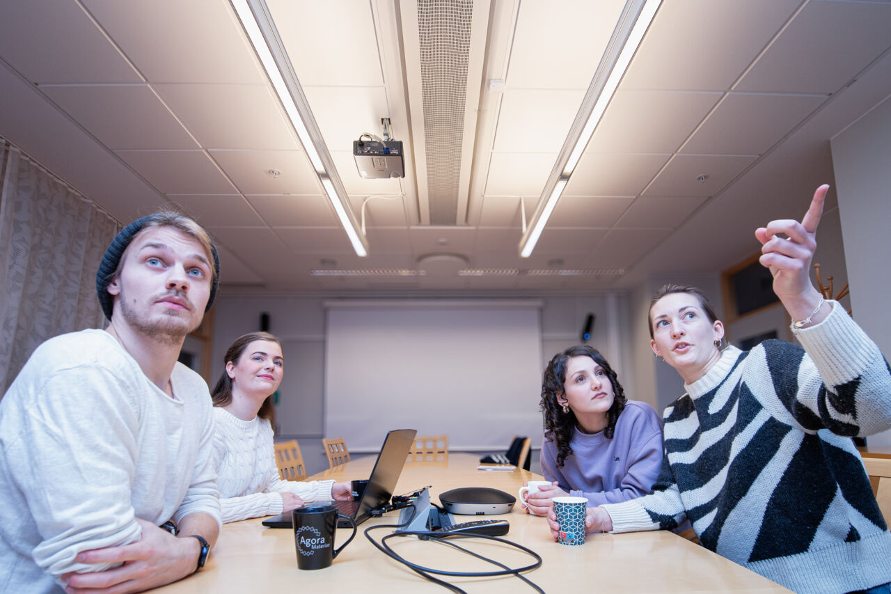 Four people at a table look towards the camera