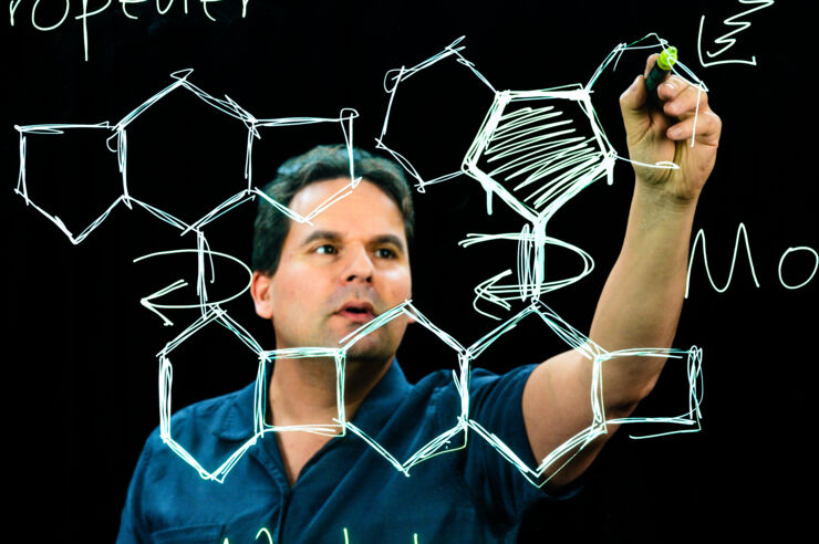 Male researcher drawing a molecule.