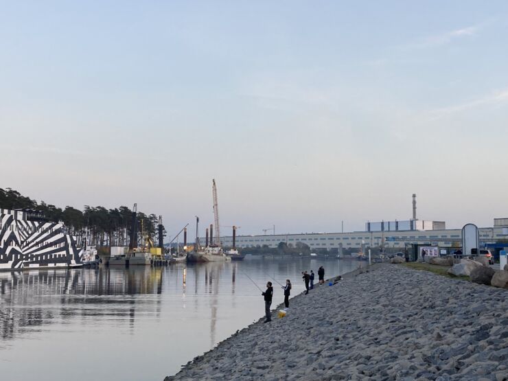 People fishing in next to a power plant