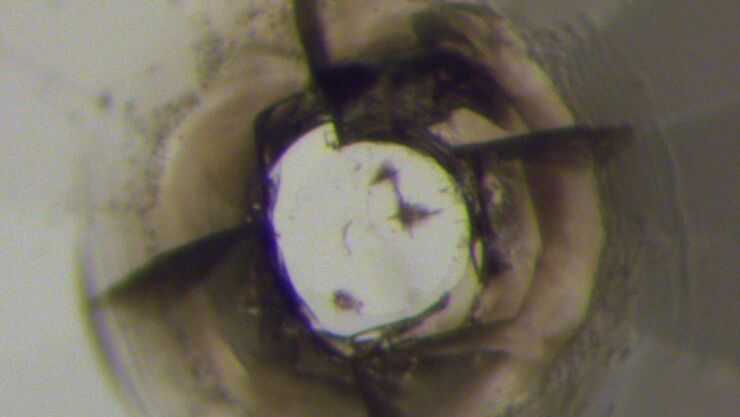 center of one of the diamonds from the diamond anvil cell pressed against the sample after decompression showing “break/indent” in the diamond with the sample, which indicates that the sample is at least of similar hardness