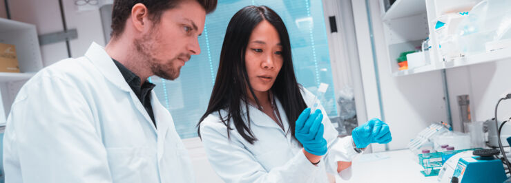 Two researchers in lab coats are working in a lab.