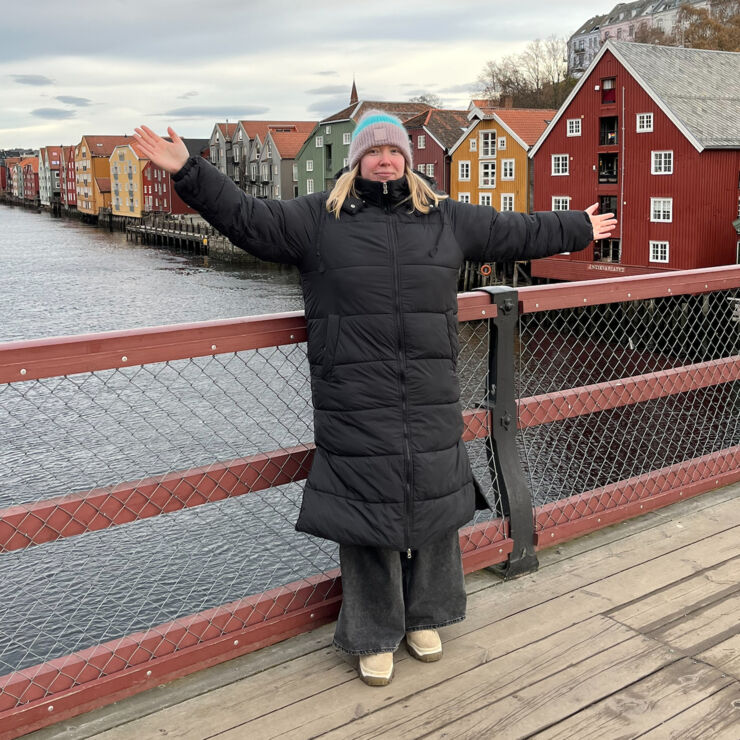 Avsnittsgäst Frida Hägglund står på en bro utomhus och håller upp sina armar.