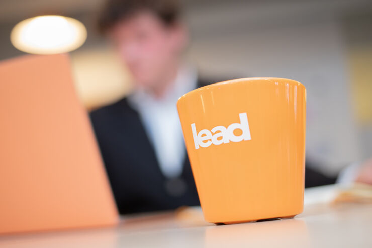 En orange mugg som det står LEAD 