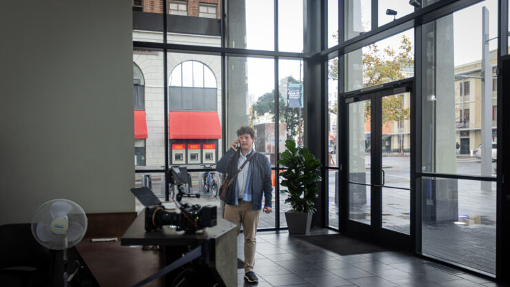 A man standing in a office lobby speaking in a cell phone