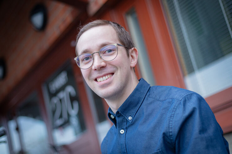 Head shot of a smiling man wearing glasses and a blue shirt