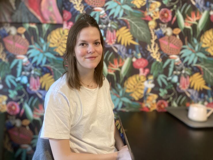 Inomhus porträtt av Ellen Mårtensson som sitter vid ett cafébord. 