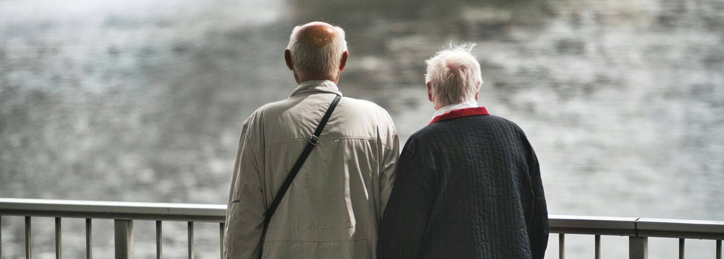Äldre par som står och tittar ut mot vatten.