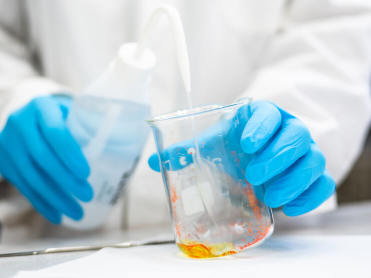 Researchers pour liquid into a beaker.