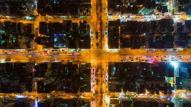 Car, taxi and bus traffic on road intersection at night in Hong Kong downtown, drone aerial view. Street commuters, Asian city life or public transport concept.