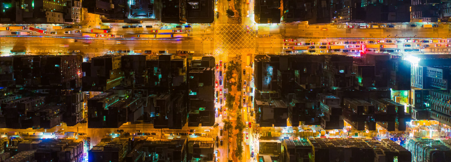 Car, taxi and bus traffic on road intersection at night in Hong Kong downtown, drone aerial view. Street commuters, Asian city life or public transport concept.