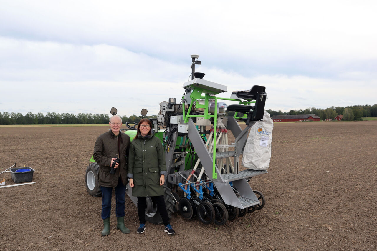 Per Frankelius och Karolina Muhrman på en åker framför en jordbruksmaskin.