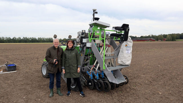 Per Frankelius och Karolina Muhrman på en åker framför en jordbruksmaskin.