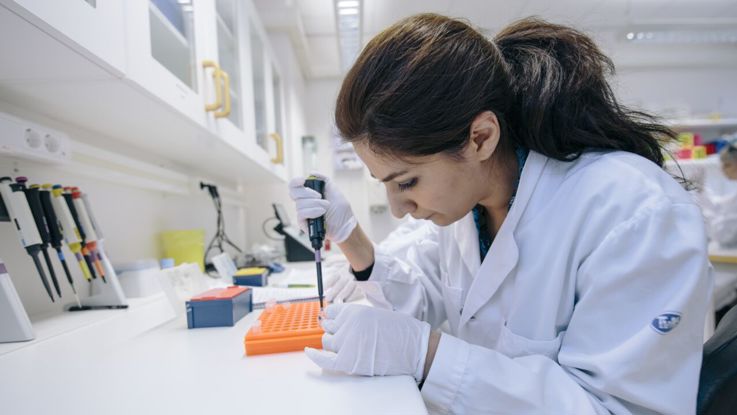 Kvinna i vit rock analyserar prover i ett labb.