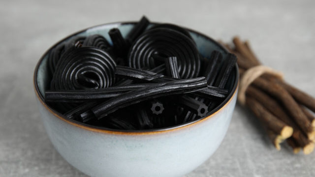 Liqourice in a bowl with liquorice roots next to it.