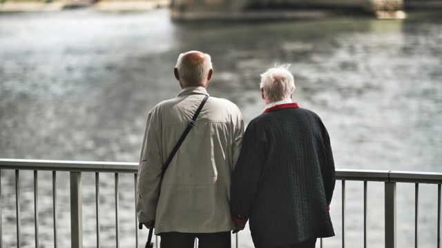 Äldre par som står och tittar ut mot vatten.