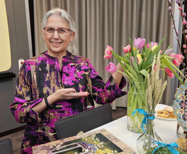 Mariam Kamkar gesturing to the table decorated with flowers and symbols for Nowruz