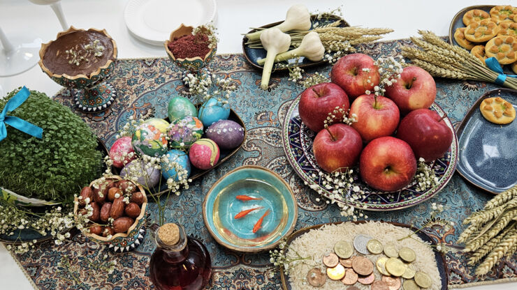 Matbord med symboler för Nouruz som ris, mynt, ägg, veteax