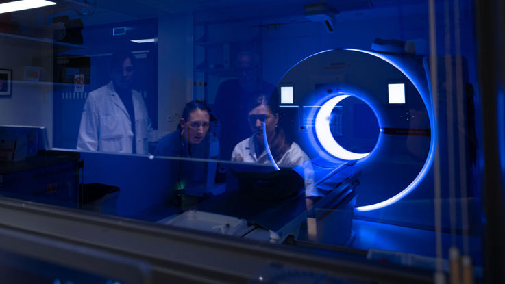 Four researchers in the control room of a photon-counting CT scanner.