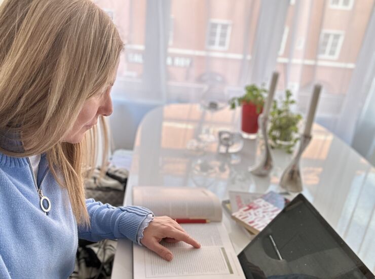 Kvinnlig student sitter vid köksbord och studerar.